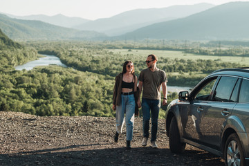 Young Traveler Couple on a Road Trip, Man and Woman Enjoying Journey on Their Car Over Beautiful Landscape