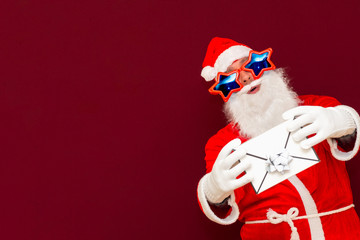 Fake Bearded man in Santa Claus hat holds gift letter envelope box. Ch hristmas gift. Christmas or New Year holidays.