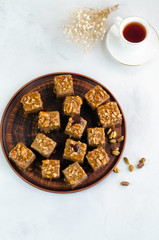Chocolate fudge bars with nuts on a brown plate on a white background. Clean eating concept. Raw vegan dessert. Flat lay