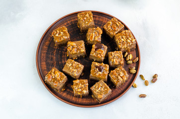 Chocolate fudge bars with nuts on a brown plate on a white background. Clean eating concept. Raw vegan dessert. Flat lay
