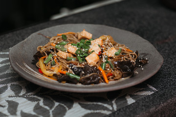 beautiful top view of ready-made dish in a restaurant healthy ingredients fish tuna tomato greens sesame seeds noodles traditional asian cuisine