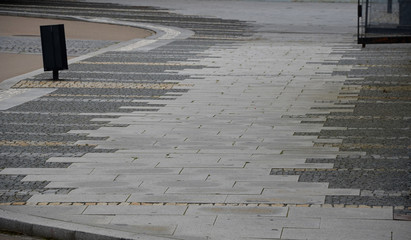 paving gray brown beige color of natural stone boulders of irregular shapes and colors. Benches around a square and rectangular tree lined with wood on a staircase