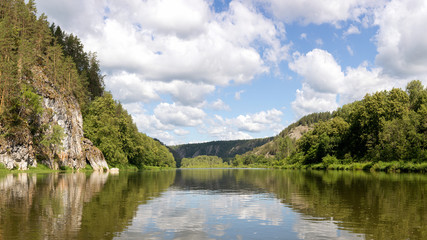 Fototapeta na wymiar Panoramic view of water surface from the middle of Belaya mountain river. calm summer weather, clear cloudy sky. beautiful reflection of sky in water