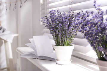 Beautiful lavender flowers and book on window sill indoors