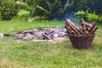 camp fire in the garden, next to a basket with firewood