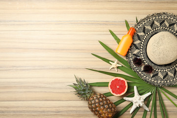 Flat lay composition with fruits and beach objects on wooden background. Space for text