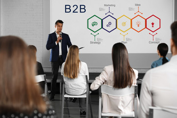 Business trainer giving lecture in conference room with projection screen