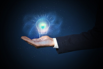 Idea concept. Businessman demonstrating glowing light bulb illustration on dark background, closeup