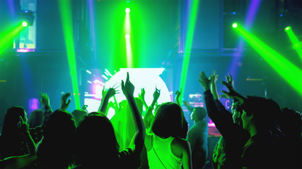 crowd of people raise hands and dancing in night club