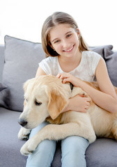 Smiling teenage girl with adorable dog in light room