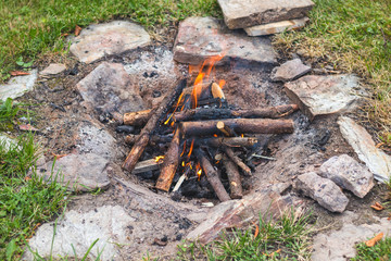 camp fire in the garden, stones around, in summer day