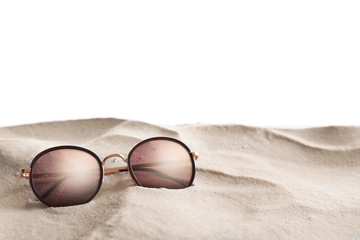 Stylish sunglasses on sand against white background. Space for text