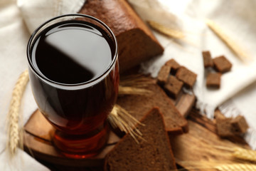 Glass of delicious kvass, spikes and bread on wooden table. Space for text