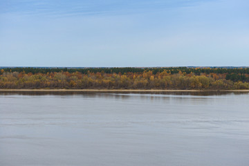 Distant sandy riverbank with autumn forest on a cloudy afternoon