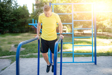 Man pulling up on parallel bars during street training