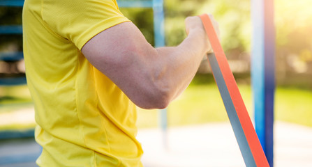 Male muscular arm with elastic rubber band in street