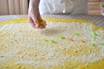 woman's hand sprinkles the dough with candied fruits and raisins