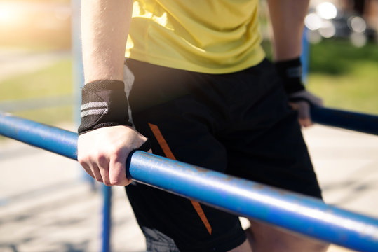 Man pulling up on parallel bars during street training