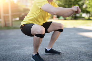 Man doing squat in knee support bandage during street workout