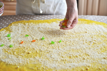 woman's hand sprinkles the dough with candied fruits and raisins