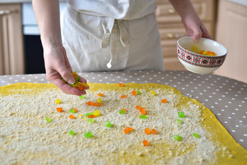 woman's hand sprinkles the dough with candied fruits and raisins