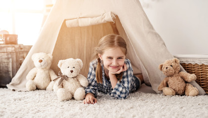 Smiling little girl lying in wigwam with teddy bears, panoramic orientation © Ievgen Skrypko