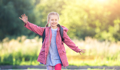 Happy little girl running outdoors after class on nature background