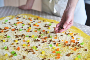 woman's hand sprinkles the dough with candied fruits and raisins