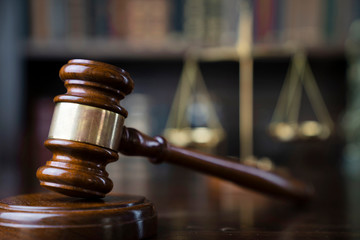 Law theme. Judge chamber. Gavel and scale on brown shining desk. Collection of legal books in the...