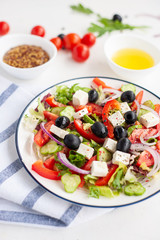 Greek vegetable salad with feta cheese and ingredients from which it is cooked on a white concrete background.