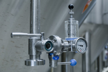 Modern equipment for tasting beer and checking quality of product in modern beer factory. Row of tanks in brewery. Fermentation in brewery tanks with beer for brewing. Big steel tanks for storage.