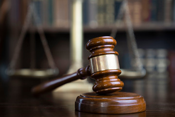Law theme. Judge chamber. Gavel and scale on brown shining desk. Collection of legal books in the...