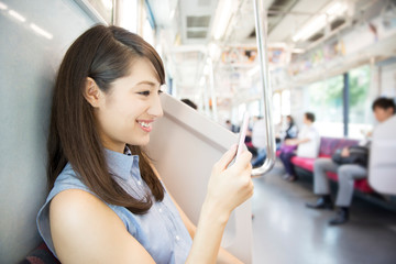 電車でスマートフォンを見る女性