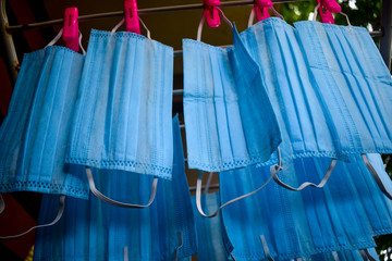 Corona Virus pandemic masks being hanged on a cloth rod after cleaning. Reusable blue colored face masks