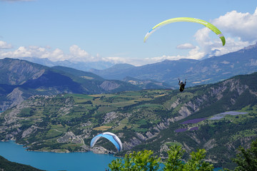 paragliding in the mountains of the french alps above serre ponçon lake