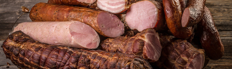 Assorted meat products including ham and sausages. ariety of processed cold meat products, Long banner format