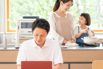 家でテレワークする男性と家族