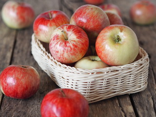 Wooden background with red early ripe apples in bulk and in a basket. Agricultural apple background.