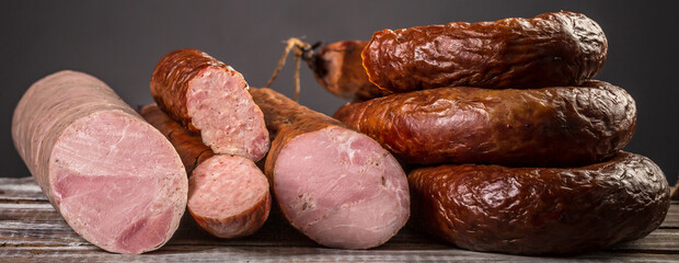 Assorted meat products including ham and sausages. ariety of processed cold meat products, Long banner format