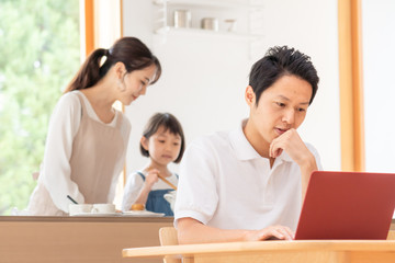 家でテレワークする男性と家族