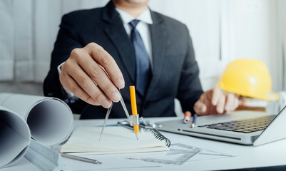 Two colleagues discussing data working and tablet, laptop with on on architectural project at construction site at desk in office