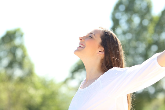 Happy woman outdoors breathing fresh air spreading arms