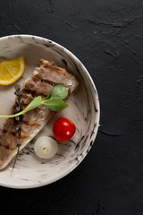Fish fried on the grill and served on a plate with fresh vegetables
