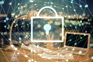 Double exposure of desktop with computer and lock icon hologram. Concept of data safety.