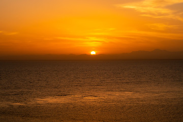 Minimal orange sunset over the Red Sea and Sudanese mountains on the horizon, tranquil evening, seen from a ship.