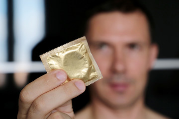 Condom in male hands close up, safe sex. Man giving condom in package, contraception concept