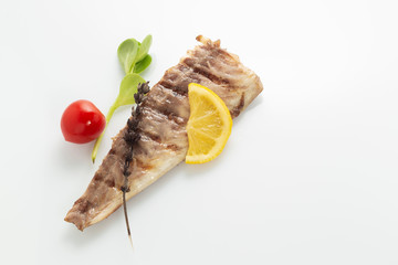 Fish fried on the grill and served on a plate with fresh vegetables