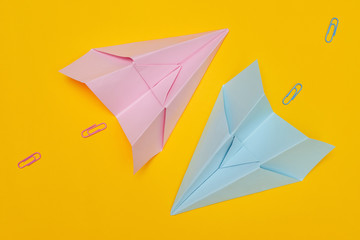 Minimalism, two blue and pink paper airplanes with paved path on yellow background, flat lay with copy space