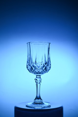 Wineglass on the light background. Fine cristal glassware concept. Vertical, toned in blue