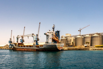 Large container ship being loaded with cargo in port in Port Sudan. Huge port cranes and row od...
